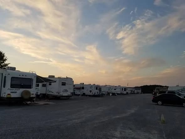 A row of RVs along the gravel lot at Heartland RV Park under a golden-hour sky