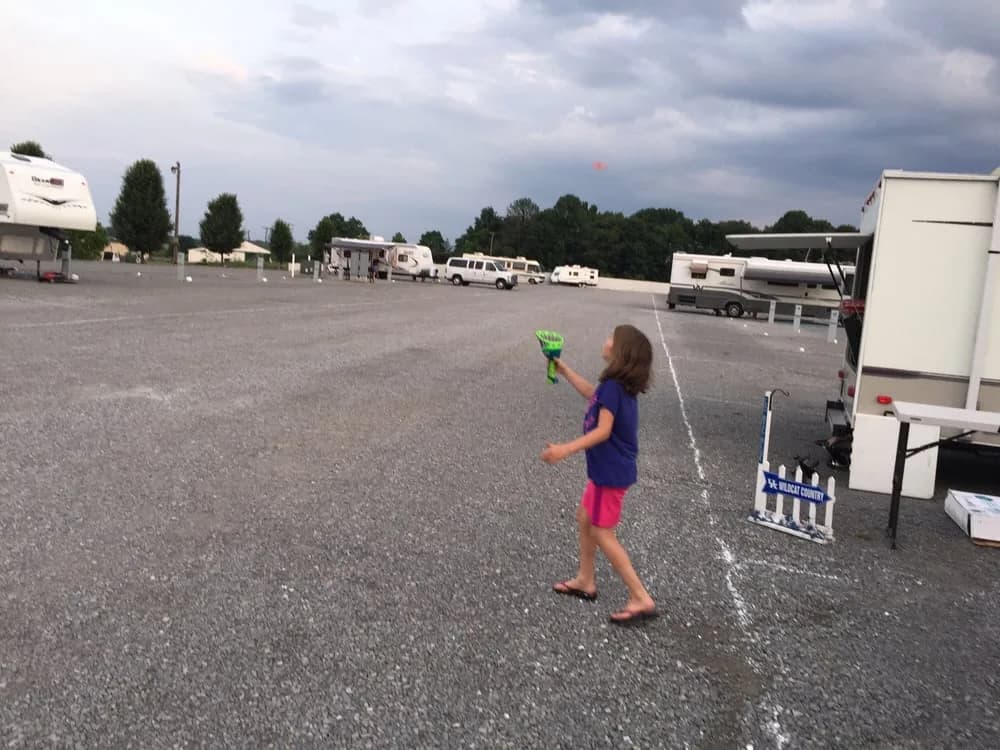 Child flying a kite on the gravel lot with RVs in the background at Heartland RV Park