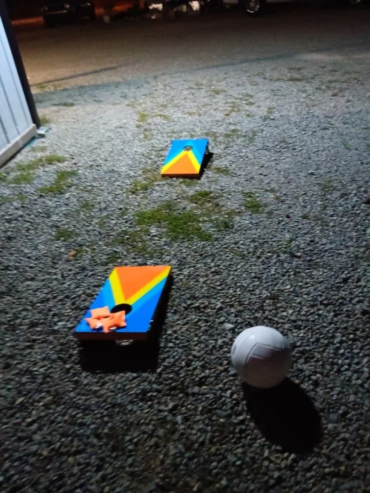 Cornhole boards lit up on the gravel lot at night at Heartland RV Park